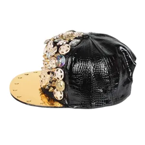 Gorra estilo punk negro textura cocodrilo, visera plana dorada y tachuelas de pedrería lujosas.