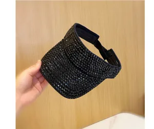 Dettaglio cappello visiera sole vuoto strass nero, protezione solare esterna estiva elegante.