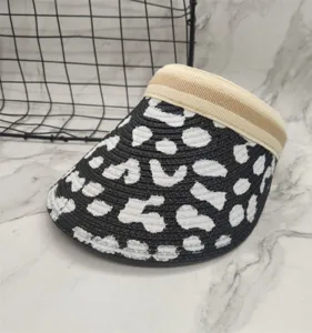Detailed view of black and white graffiti pattern sun visor with beige striped band.