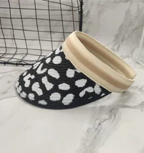 Cow print straw sun visor hat, empty top design with beige headband for summer outdoor wear.