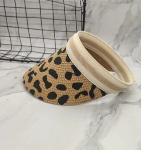 Detailed close-up of a stylish leopard print straw sun visor hat with wide headband design.