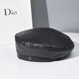 Detailed view of black PU leather beret with metal M logo, retro British style hat closeup