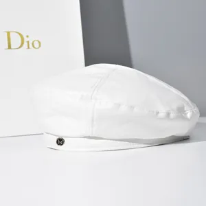 Close-up of the white PU leather beret, highlighting texture and metal M logo detail.