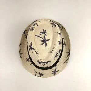 Vue detaillee du chapeau de paille avec motif de palmier et bande foncee, accessoire de plage.