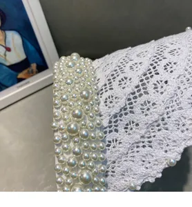 Close-up detail shot of the elegant pearl-embellished white lace empty top sun hat texture.