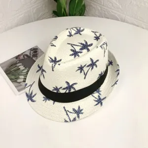 Gros plan détaillé du chapeau de paille blanc avec motif de palmiers bleus et ruban noir.