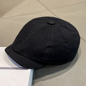 Detail shot of a classic black octagonal cap, showcasing fine stitching and fabric texture.