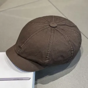 Brown newsboy cap detail, retro octagonal hat texture and stitching close up view.
