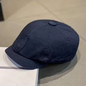 Detailed view of dark blue cotton newsboy cap, classic stitching, casual retro hat style.