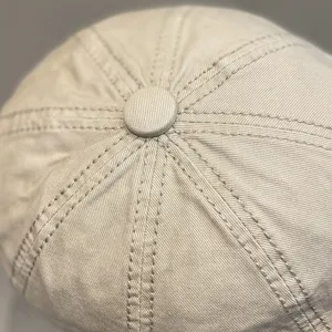 Close-up detail view of the stitching and top button on a classic neutral beige octagonal hat.