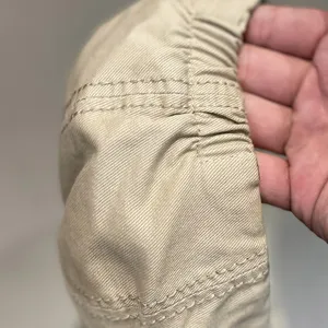 Close-up detail shot of khaki twill beret cap showing fine stitching and elastic band craftsmanship.