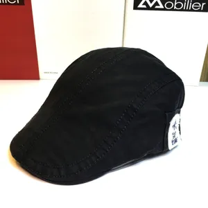 Classic black cotton flat cap detail view, showing fine stitching and side patch decoration.