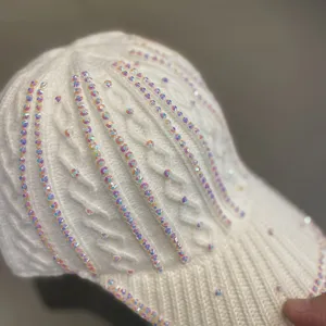 Detail de la casquette de baseball en tricot strassée montrant des cristaux brillants sur laine blanche.