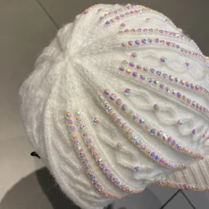 Vue détaillée d'une casquette de baseball en tricot blanc ornée de strass irisés scintillants.