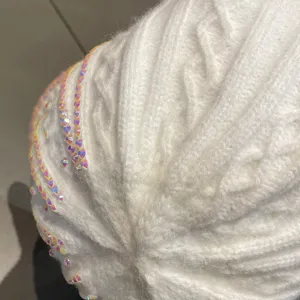 Vue de détail de casquette de baseball en tricot blanc avec strass brillants, élégante et chaude.