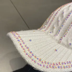 Gros plan d'une casquette de baseball tricotée blanche avec des strass irisés scintillants.