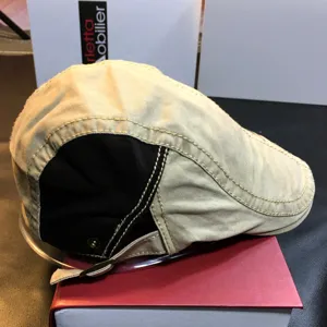 Detailed view of the casual patchwork flat cap in beige and black with contrast stitching.