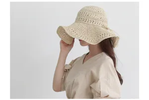 Detailed view of women's beige woven straw sun hat, wide brim bohemian beach hat for summer.