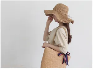 Detail view of the wide brim straw sun hat and woven beach bag, elegant summer style.