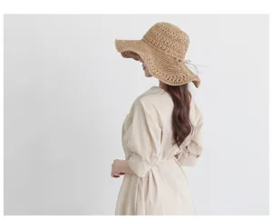 Detail view of the boho woven straw sun hat, featuring a wide brim and elegant ribbon bow tie.