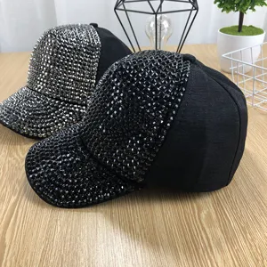 Close-up detail of stylish women rhinestone baseball caps with sparkling crystals on wooden table.