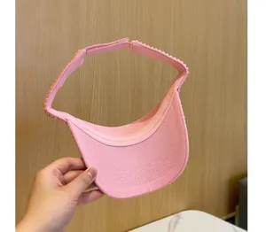 Dettaglio cappello visiera sole strass rosa, berretto aperto brillante per estate all'aperto.