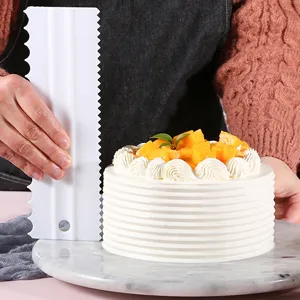 White plastic cake scraper comb tool for baking smoothing and decorating cream cakes detail shot.