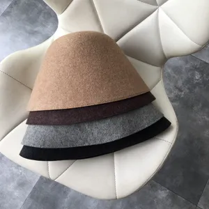 Detail view of four-color wool felt bucket hats stacked neatly on a white chair, autumn winter.