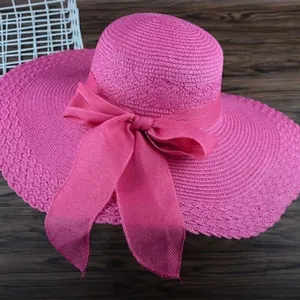 Stilvoller rosa Strohhut mit breiter Krempe und Schleife für den Sommer am Strand