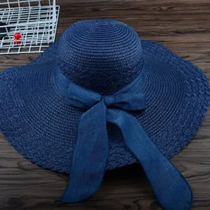Schicker dunkelblauer Strohhut mit breiter Krempe und Schleife, ideal fuer den Sommer am Strand.