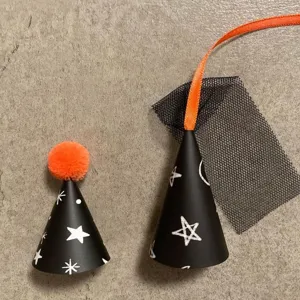 Detailed view of mini Halloween party hats with black cone shape, white stars, and orange pom.