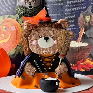 Halloween bear cake detail showing cute witch hat, broom and cauldron decoration for party.