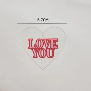 Close-up detail of acrylic heart cake topper with pink and red love you letters text.