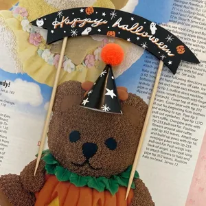 Detailed view of Halloween cake topper featuring black banner and mini cone hat decoration.