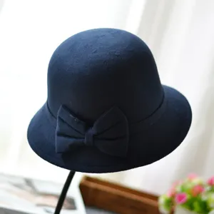 Navy blue felt cloche hat detail showing elegant side bow and neat dome crown texture.