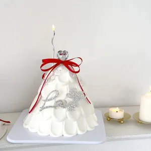 Detail shot of white decorative cone with sparkly rhinestone love letters and red ribbon.