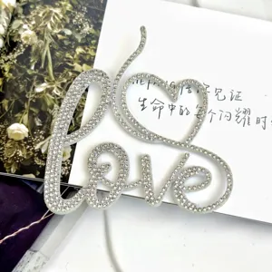 Rhinestone love cake topper detail shot, sparkling crystal letter decoration for romantic parties.