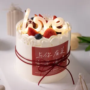 Romantic couple cake decoration with glowing love topper and strawberries for Valentine's Day party