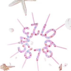 Detail close-up of pink acrylic number cake topper decorated with tiny seashells and starfish.