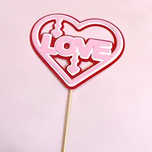 Close up detail of paper love heart cake topper insert with arrow and wooden stick for party.