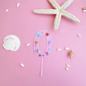 Pink acrylic number 0 cake topper with ocean shell and starfish design for birthday.