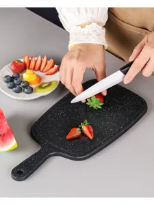 Black plastic cutting board detail showing fruit slicing scene in a clean kitchen setup.