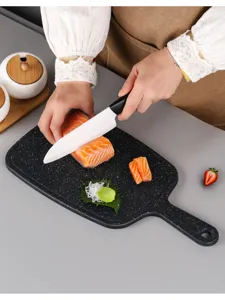 Detail view of a sturdy black plastic cutting board used in a modern kitchen setup.