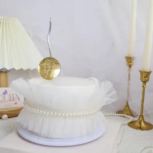 Primer plano detallado del adorno de tarta acrílico con vela ondulada y falda de tul.