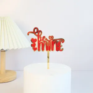 Gold and red acrylic Valentine's Day cake topper detail featuring be mine lettering and hearts.