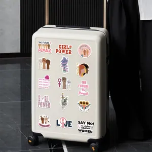 Vue rapprochée détaillée d'autocollants féministes sur une valise blanche avec slogans.