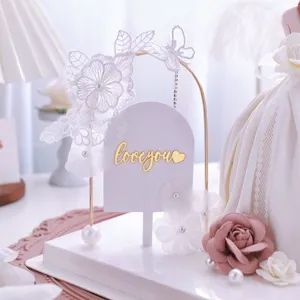 Primo piano dettagliato della decorazione per torta con arco di fiori in pizzo bianco e perle.