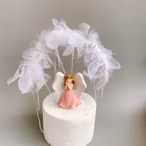 Detailaufnahme der niedlichen rosa Engelsfigur und des weißen Federbogen-Kuchendekors.