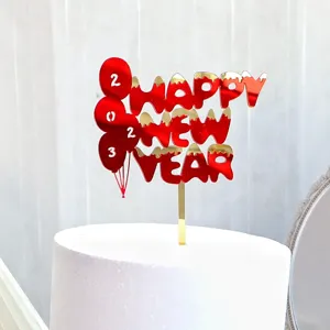 Primer plano de un adorno de tarta de acrílico rojo Feliz Año Nuevo con globos 2023 en tarta blanca.