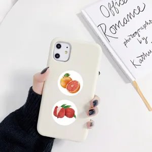 Close-up detail of a white phone case featuring cute fruit stickers like grapefruit and lychee.